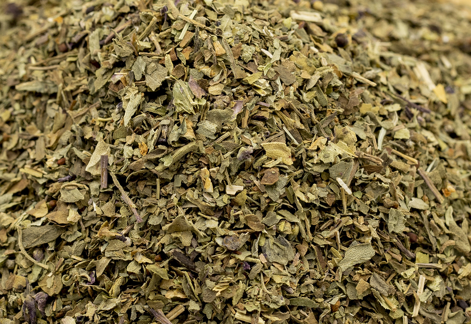 Dried crushed basil isolated on white background. Dried ground basil powder spices in wooden bowl. Spice concept